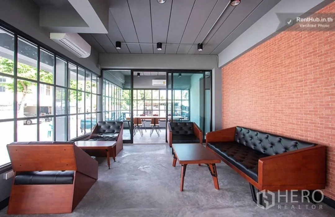 Apartment for rent in Phra Khanong, Bangkok - Lobby lounge with leather sofas, wooden tables, and floor-to-ceiling windows.
