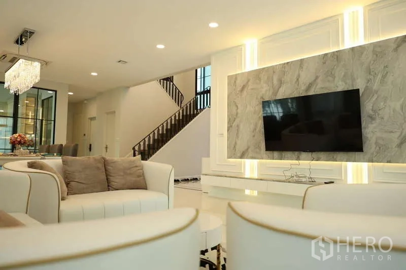 独立式住宅 出租或出售在Saphan Sung, Bangkok - 客厅设圆弧沙发，电视大理石背景与楼梯景