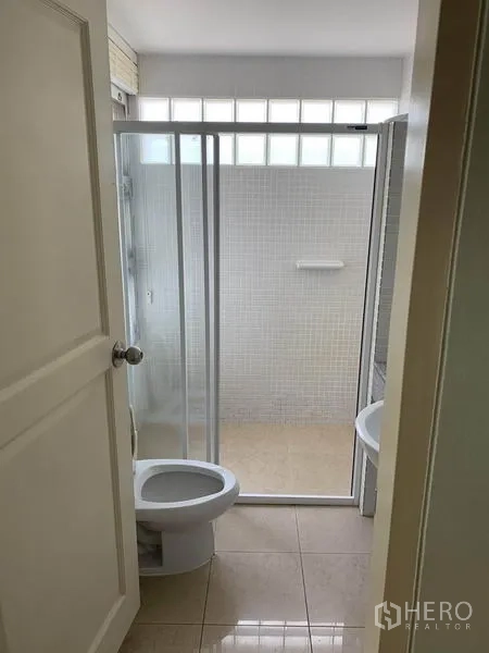 ทาวน์เฮาส์ ให้เช่าในKhlong Toei, Bangkok - ห้องน้ำพร้อมตู้กั้นอาบน้ำกระจก โถสุขภัณฑ์ และผนังกระเบื้องช่องแสงบล็อกแก้ว