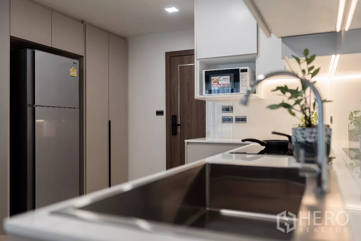 Apartment for rent - Kitchen detail showing stainless sink, tall refrigerator, cabinetry and built-in microwave.