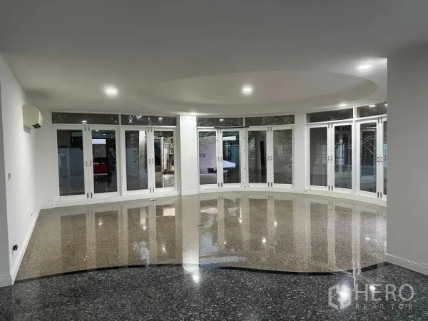 Home Office for sale - Expansive ground-floor hall with glossy terrazzo flooring, recessed circular ceiling and full-height glass doors.
