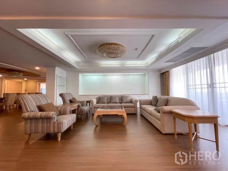 Condominium for rent in Watthana, Bangkok - Bright lounge with floor-to-ceiling curtains, chandelier, and multiple sofas.