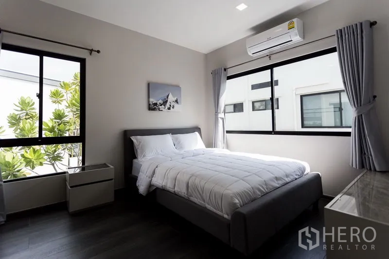 联排别墅 出租在Samut Prakan - 采光充足的次卧，双人床、大窗与空调，景观为绿树。