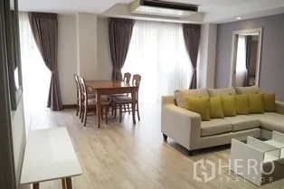 Condominium for rent in Pathum Wan, Bangkok - Lounge and dining space with large curtained windows bringing natural light.