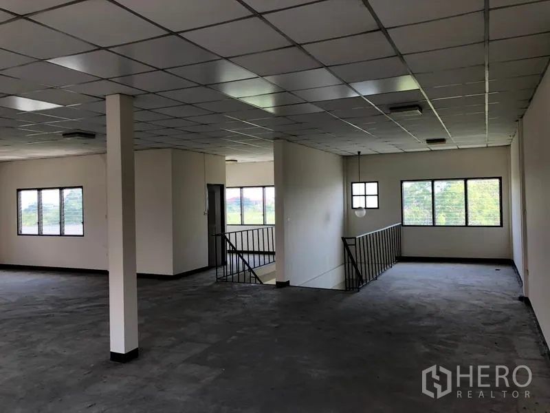 Shophouse for sale in Lam Luk Ka, Pathum Thani - Upper floor open workspace with grid ceiling and large windows bringing in natural light.