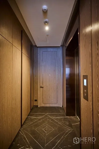 Condominium for rent in Pathum Wan, Bangkok - Private lift lobby finished with warm wood paneling and dark marble flooring.