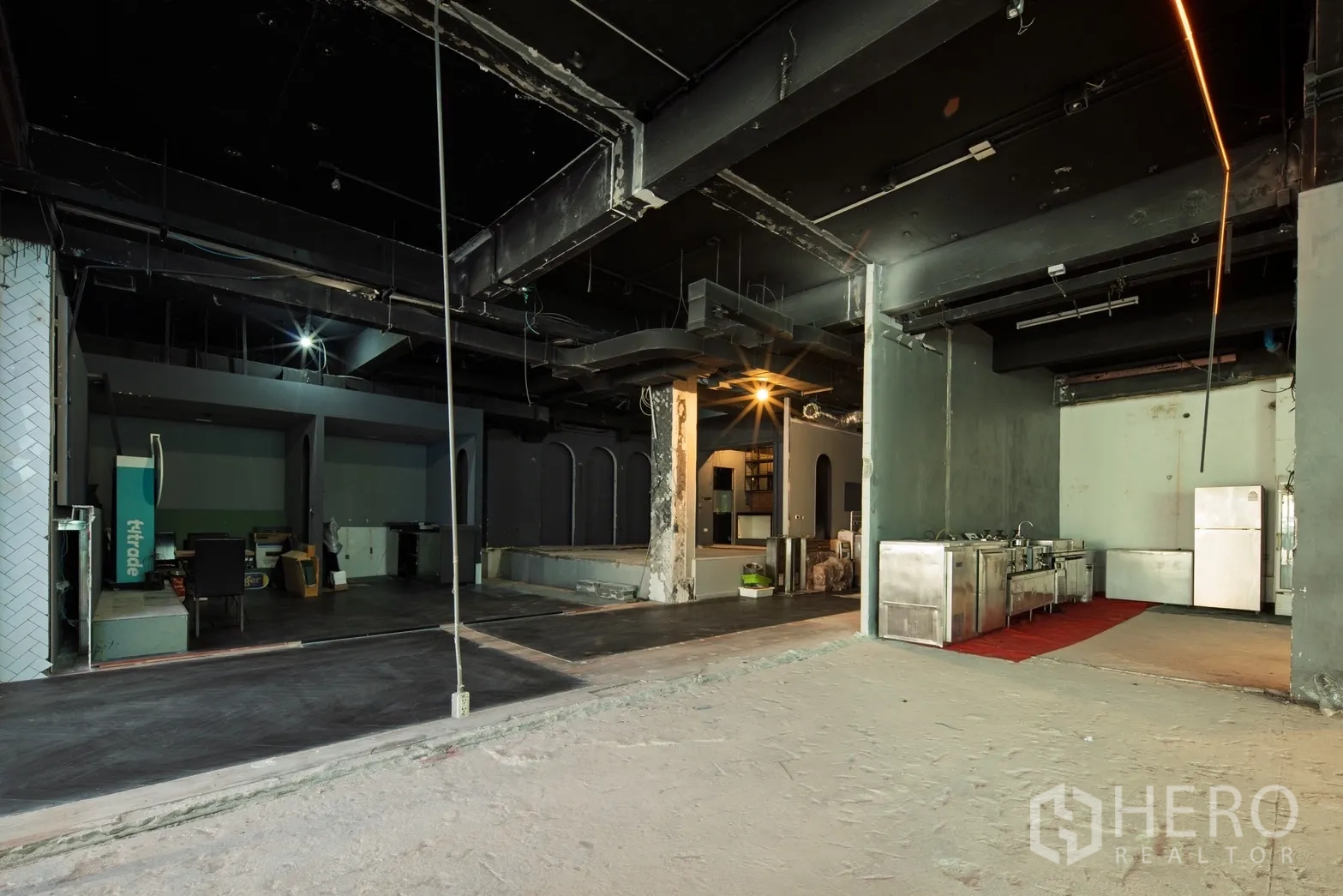 零售空间 出租在Watthana, Bangkok - 大型零售大厅，展示不锈钢备餐线、混凝土地面与立柱。