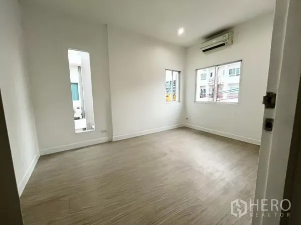 Home Office for rent in Bueng Kum, Bangkok - Bright empty room with wood-look flooring, white walls, windows and air-conditioner.