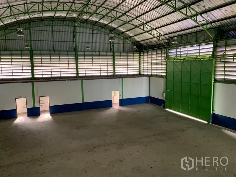 Warehouse for rent in Lam Luk Ka, Pathum Thani - Wide interior view showing the tall green sliding door, ventilation louvers and multiple access doors.