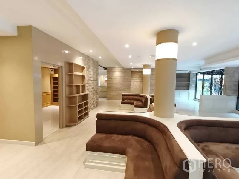 零售空间 出租在Pathum Wan, Bangkok - 室内过道，内置置物架与弧形座位，暖色装饰。