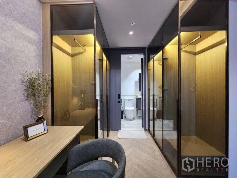 Condominium for rent in Bang Rak, Bangkok - Walk-through dressing area with illuminated glass wardrobes leading to the ensuite bathroom.