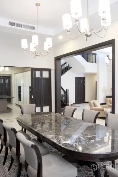 Detached House for rent in Khlong Toei, Bangkok - Elegant dining room with a marble-top table, chandeliers and a view of the staircase and lounge.
