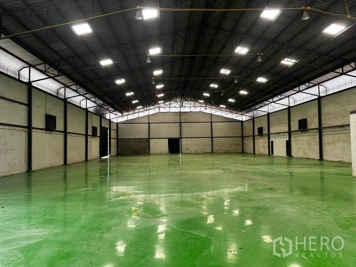 Factory for rent in Bang Phli, Samut Prakan - Spacious warehouse interior with high steel roof, bright lights, and green epoxy floor.