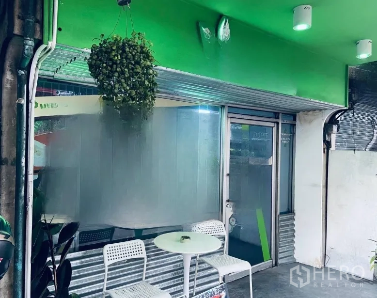 店屋 出租或出售在Khlong Toei, Bangkok - 入口前的户外小坐区，绿色雨棚下的白色圆桌与椅子。