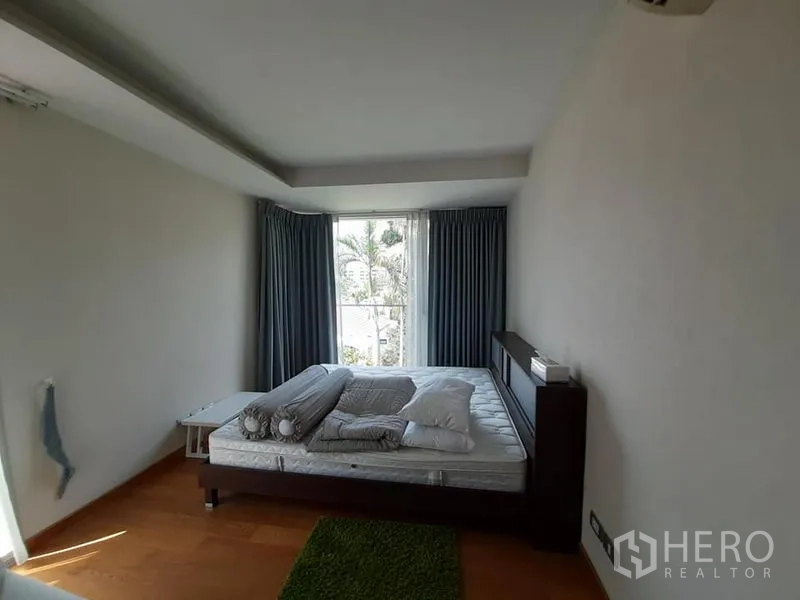 公寓 出售在Watthana, Bangkok - 主卧室配大窗与深色窗帘，木地板，窗外绿景。