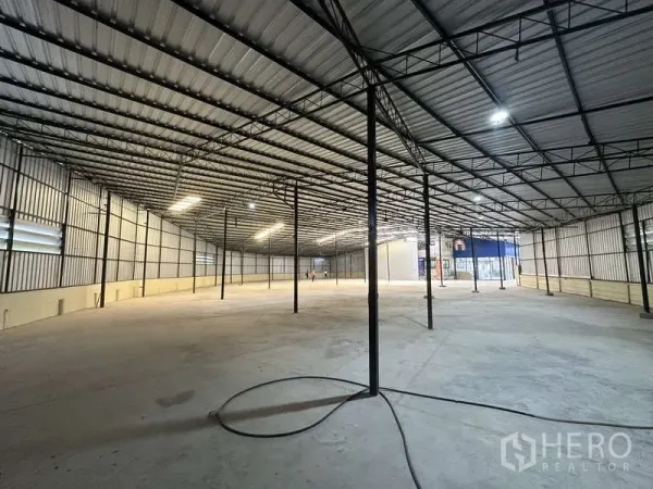 Warehouse for rent in Pak Kret, Nonthaburi - Large columned warehouse floor with bright lighting and louvered side windows for ventilation.