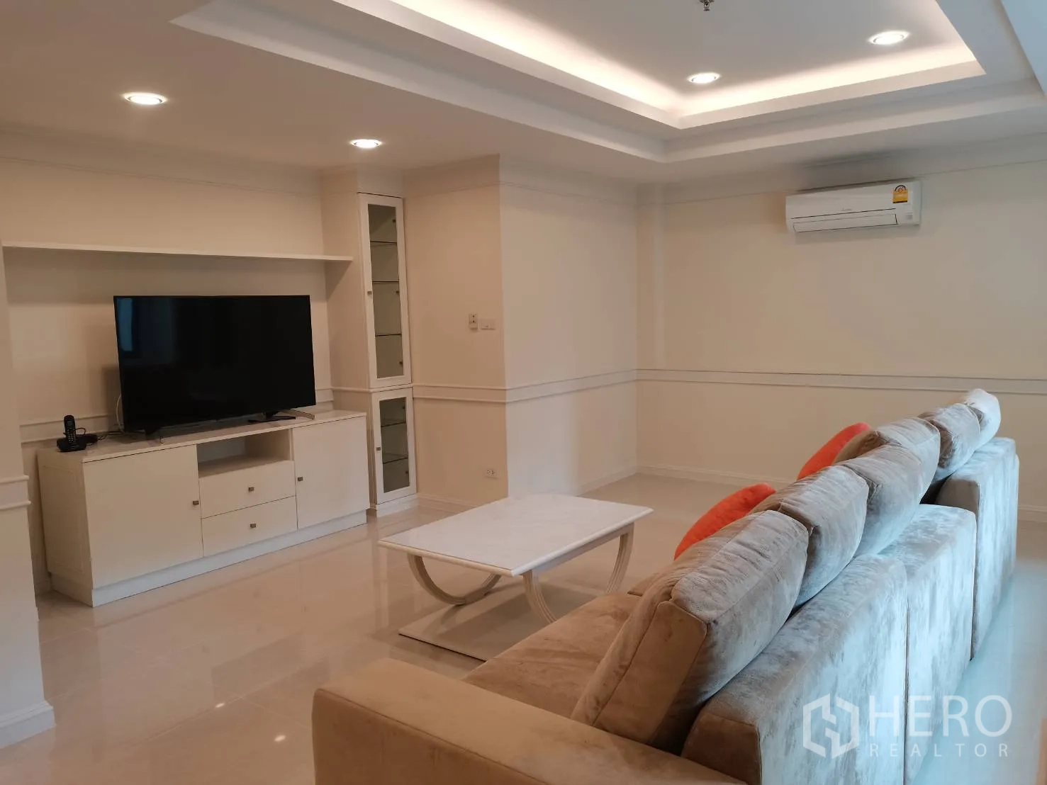 Condominium for rent in Watthana, Bangkok - Cozy living room featuring a large sectional sofa, TV console, and tray ceiling lighting.