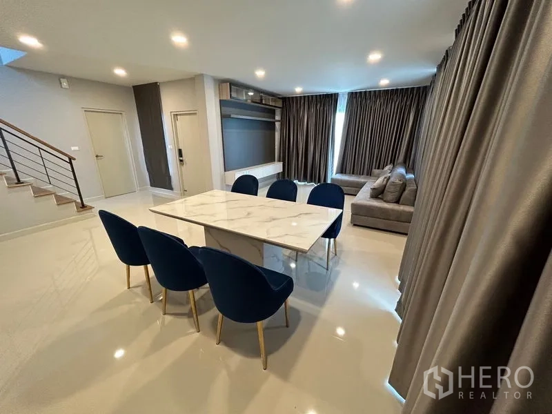 Detached House for rent in Bang Phli, Samut Prakan - Open-plan living and dining area with staircase and media wall unit.