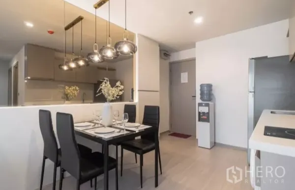Condominium for rent in Chatuchak, Bangkok - Dining table for four beside the open kitchen with pendant lamps, refrigerator and entry door.