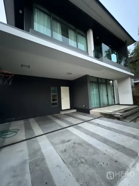 บ้าน ให้เช่าหรือขายในBang Kapi, Bangkok - ที่จอดรถมีหลังคาและพื้นคอนกรีตลายแถบใต้ระเบียงชั้นบน