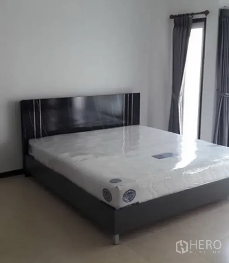 สำนักงานที่บ้าน ให้เช่าในKhlong Toei, Bangkok - ห้องนอนสว่างพร้อมเตียงใหญ่ หัวเตียงสีเข้ม และหน้าต่างสูงพร้อมผ้าม่านสีเทา