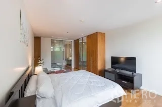 Condominium for rent in Bang Rak, Bangkok - Primary bedroom with wardrobes, TV unit and sliding glass doors to ensuite.