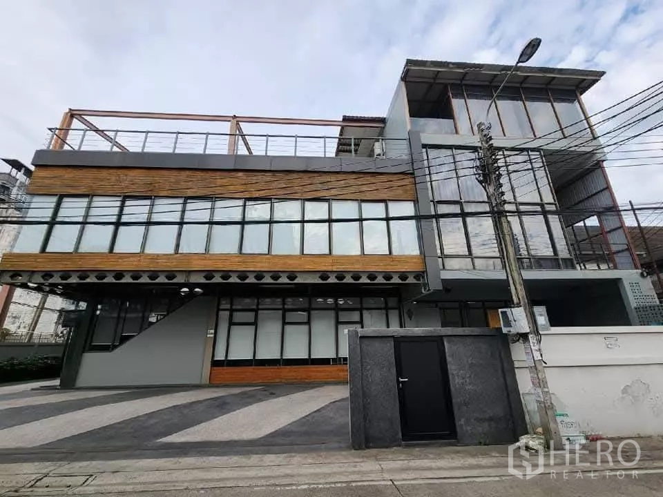 Home Office for rent in Mueang Nonthaburi, Nonthaburi - Modern three-storey home office facade with glass walls and wood cladding in Nonthaburi.