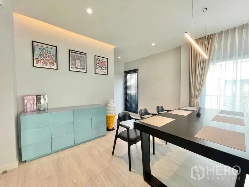 Detached House for rent in Bang Phli, Samut Prakan - Dining area with sleek black table, pendant light and pastel sideboard with wall art.