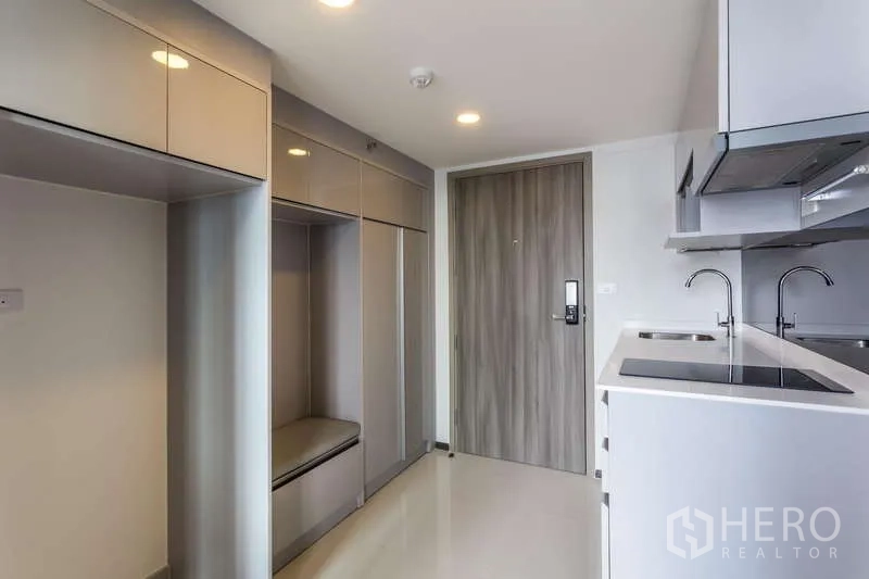 Condominium for rent or sale - Entry foyer with built-in cabinetry opposite a linear kitchen.