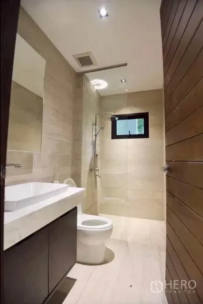 Townhouse for rent in Din Daeng, Bangkok - Compact bathroom with walk-in shower, wall-mounted vanity, toilet and neutral tiles.