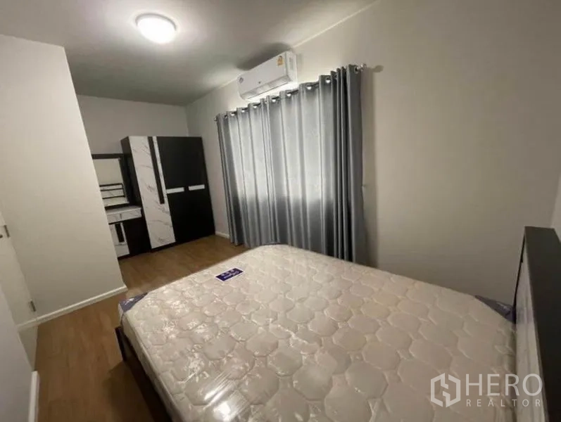 Townhouse for rent in Phasi Charoen, Bangkok - Air-conditioned bedroom with double bed, wardrobe, dressing table and curtains.