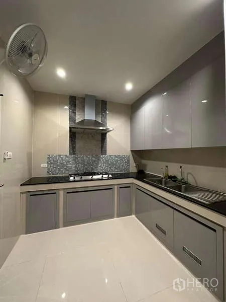 独立式住宅 出售在Prawet, Bangkok - 嵌入式厨房，灰色橱柜、黑色台面、燃气灶与油烟机。
