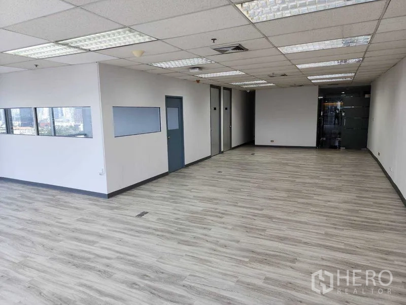 办公空间 出租在Phra Khanong, Bangkok - 宽敞明亮的办公区，荧光灯、木地板、侧窗与玻璃入口门。