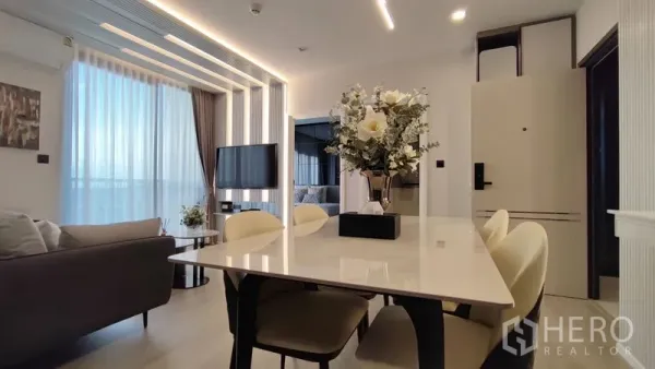 Condominium for rent in Bang Kho Laem, Bangkok - Dining table view toward the living zone and bedroom, with modern pendant lights and floor-to-ceiling glazing.