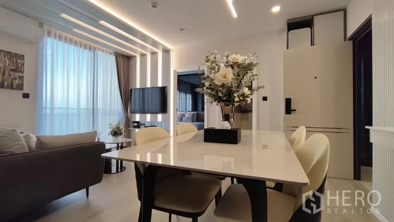 Condominium for rent in Bang Kho Laem, Bangkok - Dining table view toward the living zone and bedroom, with modern pendant lights and floor-to-ceiling glazing.