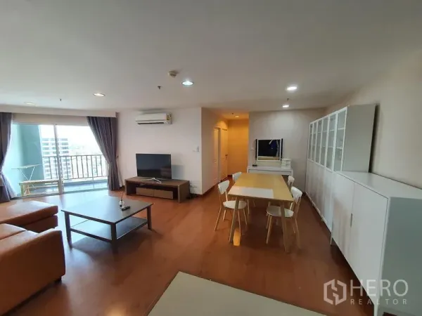 Condominium for rent in Huai Khwang, Bangkok - Open-plan living and dining area with TV, cabinets and balcony access in condo close to MRT Phra Ram 9.
