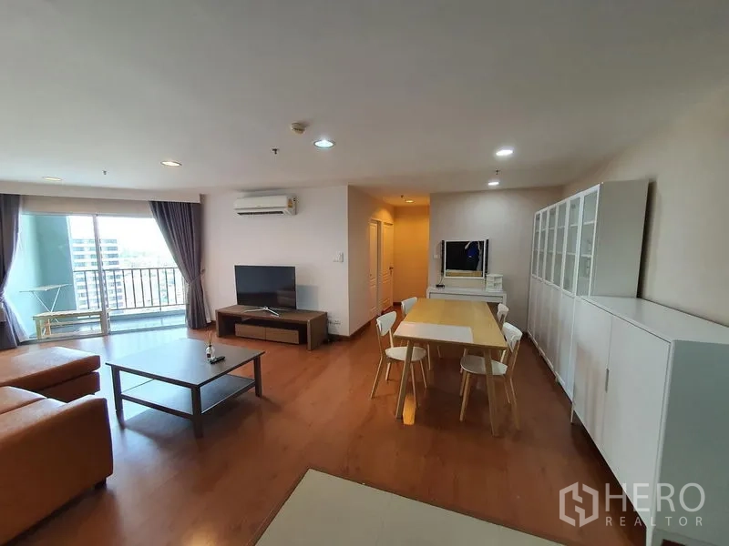 Condominium for rent in Huai Khwang, Bangkok - Open-plan living and dining area with TV, cabinets and balcony access in condo close to MRT Phra Ram 9.