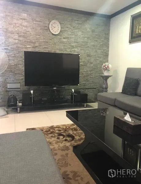 ทาวน์เฮาส์ ให้เช่าในKhlong Toei, Bangkok - มุมนั่งเล่นพร้อมทีวีจอแบน ผนังลายหิน พรม และชุดโซฟา