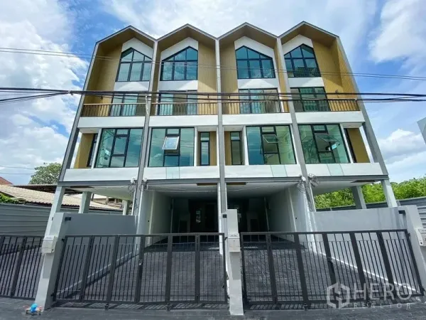 带办公室的家 出租或出售在Bang Na, Bangkok - 四层现代住办公楼外立面，尖顶设计，整面落地窗与带门庭的停车区。