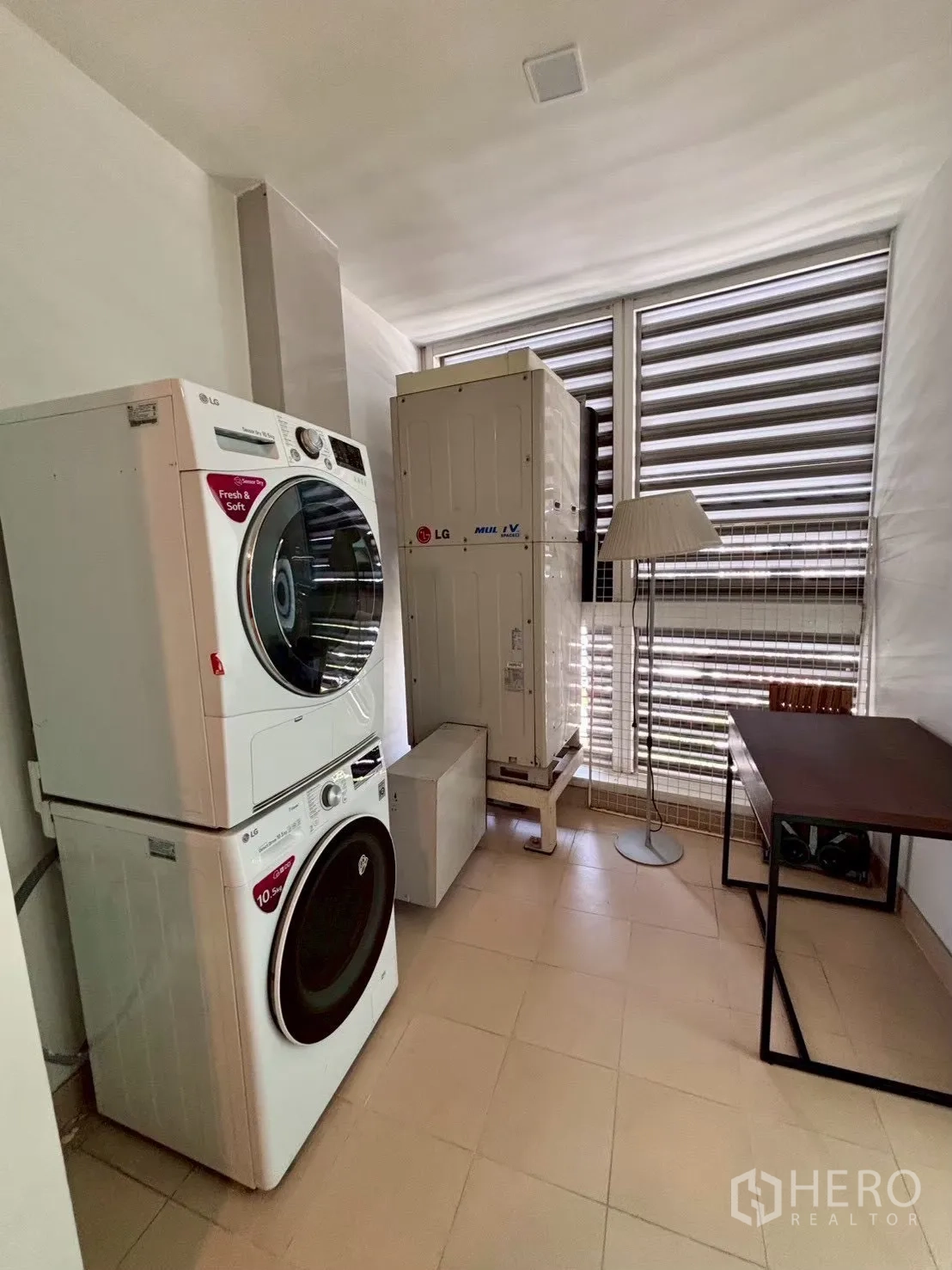 Condominium for rent in Khlong Toei, Bangkok - Utility room with stacked LG washer and dryer, air-conditioning units, desk and louvered window