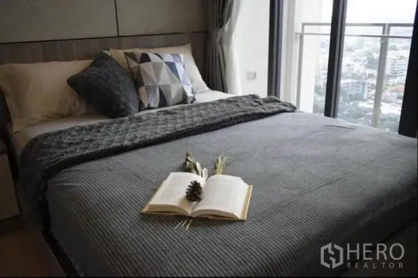 公寓 出租或出售在Phaya Thai, Bangkok - 卧室铺灰色床品，阳台门外可见城市天际线。