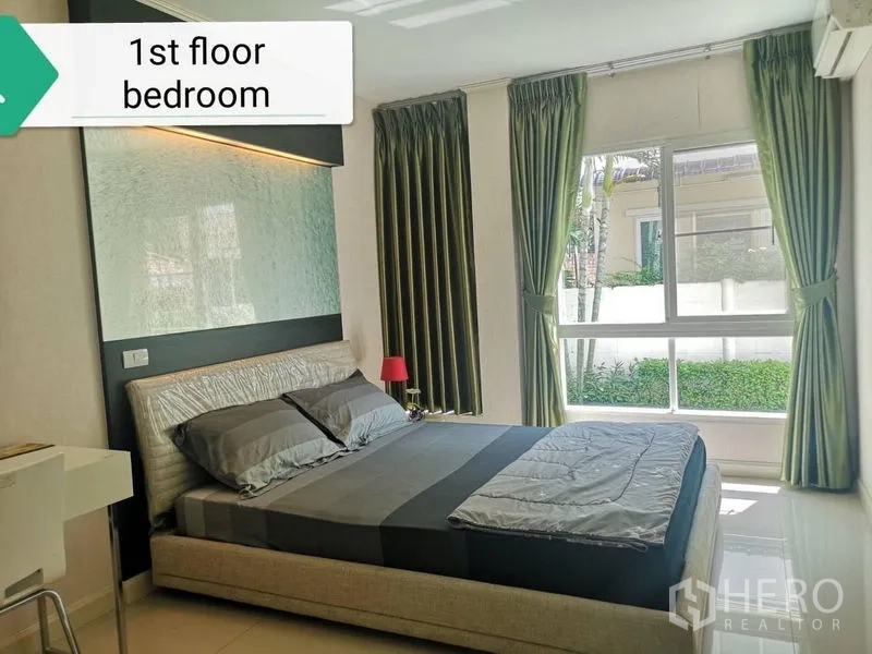 บ้าน ให้เช่า - ห้องนอนชั้นล่าง หน้าต่างบานใหญ่ ผ้าม่านสีเขียว และเตียงหุ้มบุ