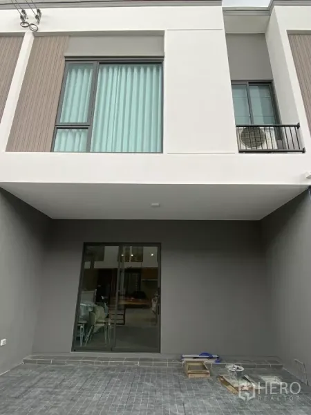 Townhouse for rent in Bang Phli, Samut Prakan - Modern two-storey townhouse facade with large windows, covered carport and sliding glass door.