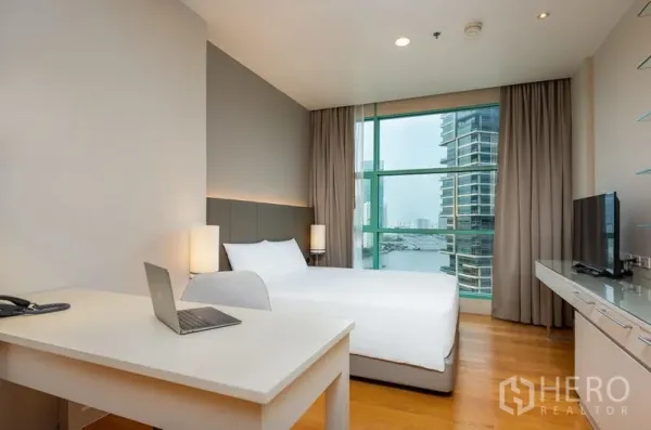 Condominium for rent in Bang Kho Laem, Bangkok - Bedroom with large window and desk offering panoramic river and city views.