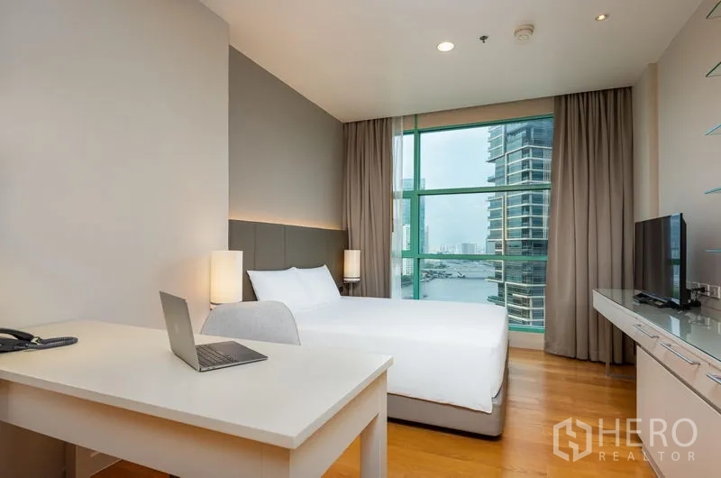 Condominium for rent in Bang Kho Laem, Bangkok - Bedroom with large window and desk offering panoramic river and city views.