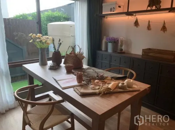 独立式住宅 出售在Bang Kapi, Bangkok - 餐厅或书房，木质餐桌、内置柜及推拉玻璃门通向庭院。