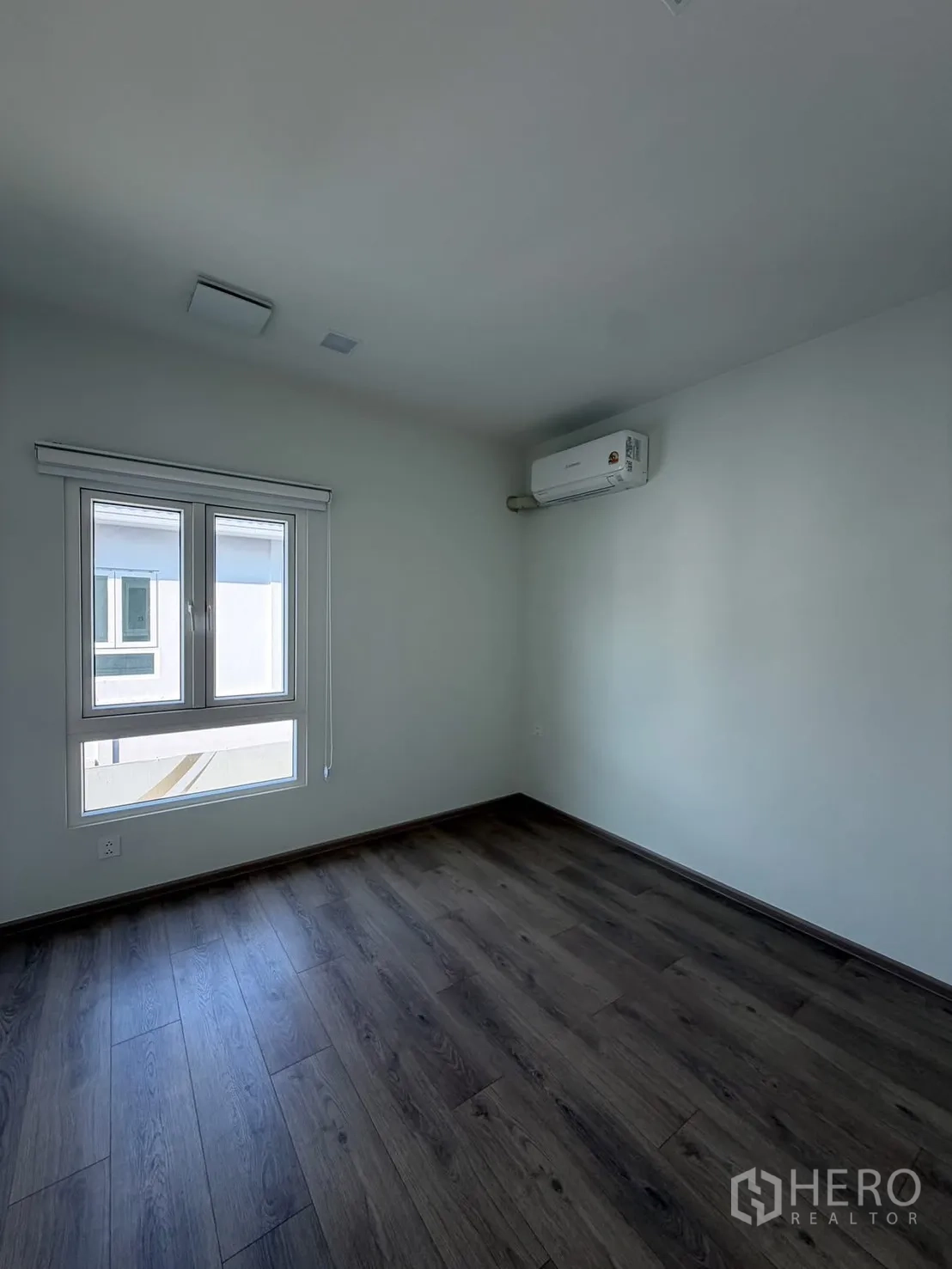 บ้าน ให้เช่าในBang Na, Bangkok - ห้องนอนโล่ง พื้นไม้สีเข้ม หน้าต่าง และแอร์แขวนผนัง