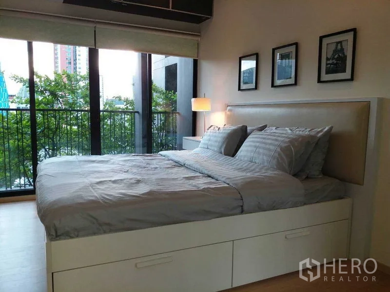 คอนโด ขายในWatthana, Bangkok - ห้องนอนมีประตูกระจกบานใหญ่ เปิดสู่ระเบียงชมวิวต้นไม้ในเมือง.