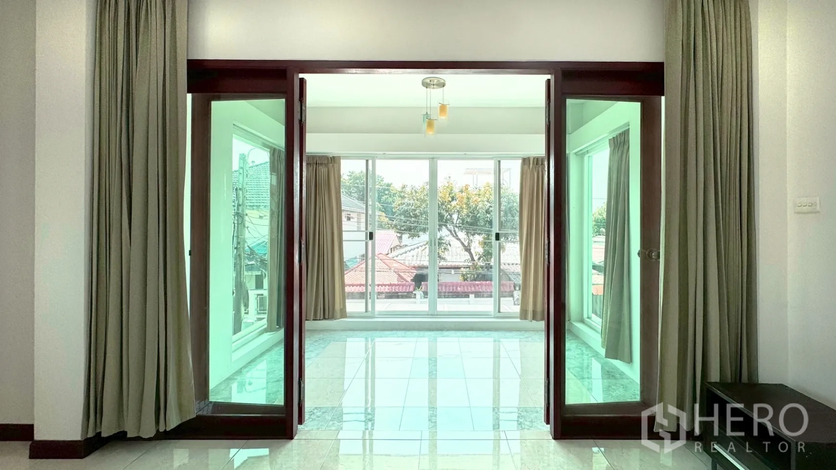 独栋房屋 for rent in Suan Luang, Bangkok - 楼上玻璃封闭日光房，通过木框推拉门进入并配有窗帘。