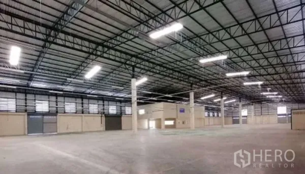 Warehouse for rent in Bang Bo, Samut Prakan - Open warehouse floor with high ceiling, columns, roller shutters and ample lighting.